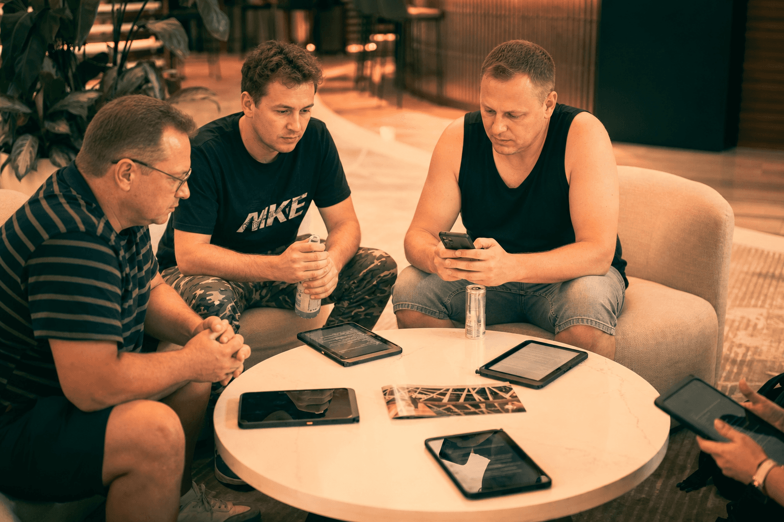Drużyna przy stoliku z tabletami SurvivorQuest w hotelowym lobby.
